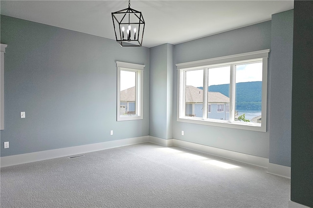 spare room with light carpet, a mountain view, and a chandelier