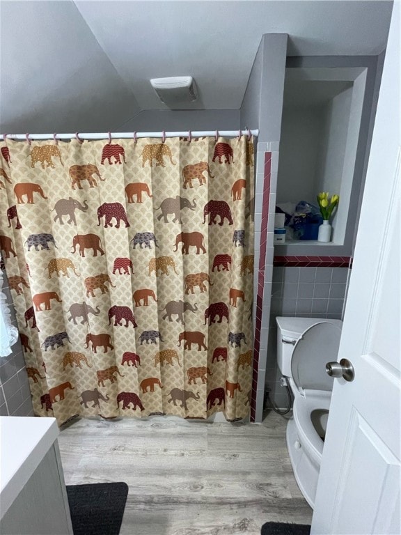 bathroom with tile walls, toilet, hardwood / wood-style floors, and vanity