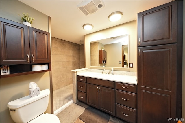 bathroom with tiled shower, toilet, tile patterned floors, and vanity