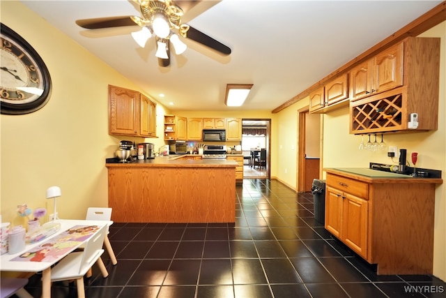 kitchen with ceiling fan, dark tile patterned flooring, stove, and kitchen peninsula