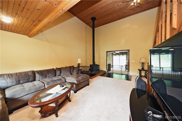 living room featuring carpet, ceiling fan, a wood stove, and wood ceiling