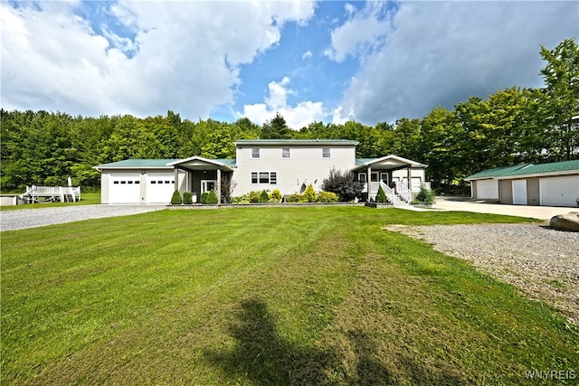 view of front of house featuring a front lawn, a garage, and an outbuilding