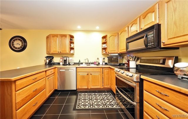 kitchen featuring sink, kitchen peninsula, appliances with stainless steel finishes, and dark tile patterned floors