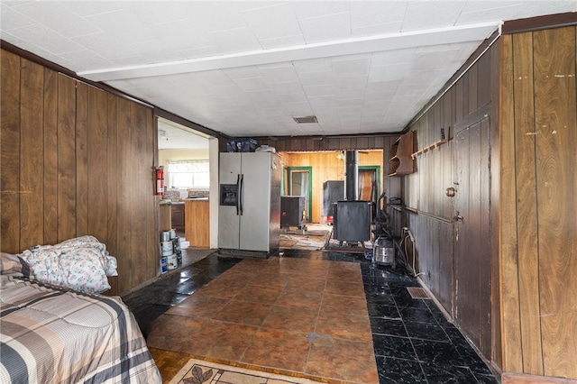 living room with a wood stove, wood walls, and dark tile patterned floors