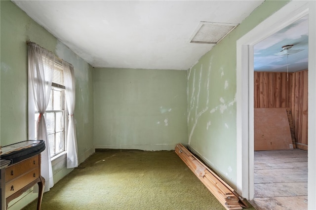 carpeted spare room with wooden walls