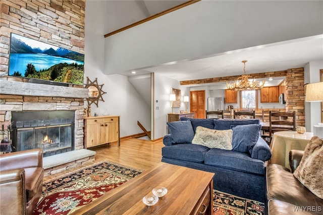 living room with light hardwood / wood-style flooring, a notable chandelier, and a stone fireplace