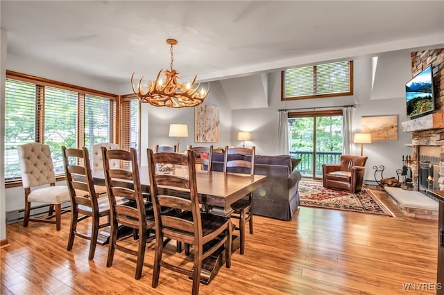 dining area featuring a fireplace, light hardwood / wood-style flooring, an inviting chandelier, and a baseboard heating unit