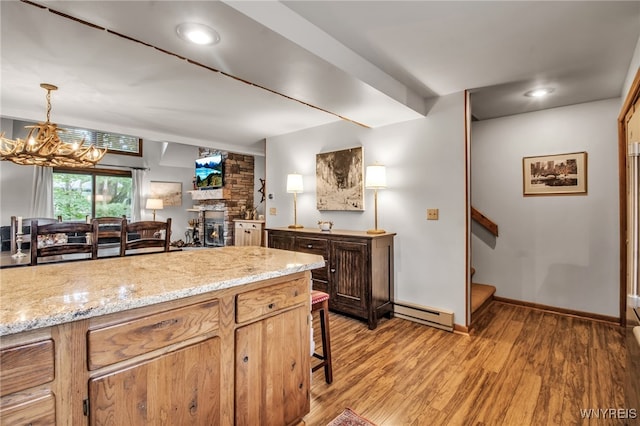 kitchen with brick wall, hanging light fixtures, a baseboard radiator, hardwood / wood-style flooring, and a fireplace