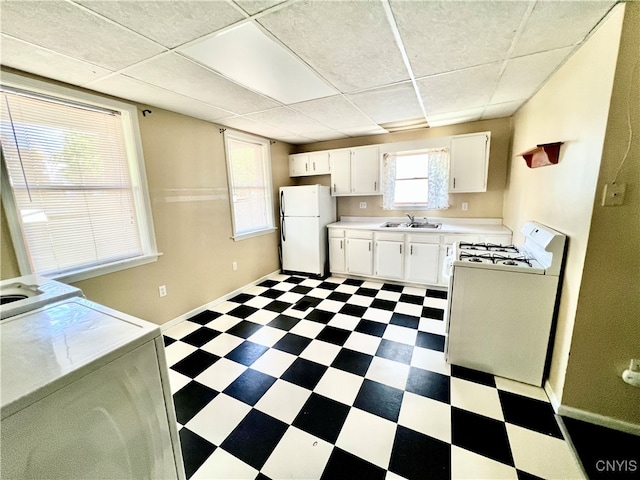 kitchen with a paneled ceiling, white cabinetry, sink, light tile patterned flooring, and white appliances