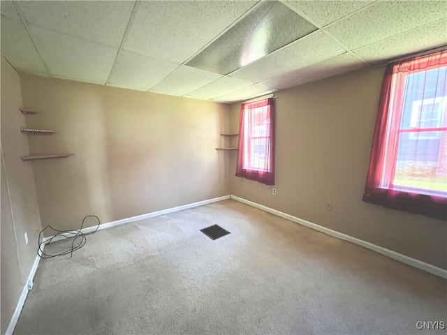 carpeted empty room featuring a wealth of natural light and a paneled ceiling