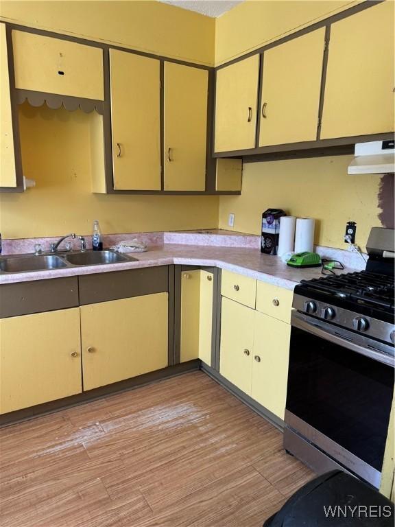 kitchen featuring sink, light wood-type flooring, stainless steel gas range oven, and range hood