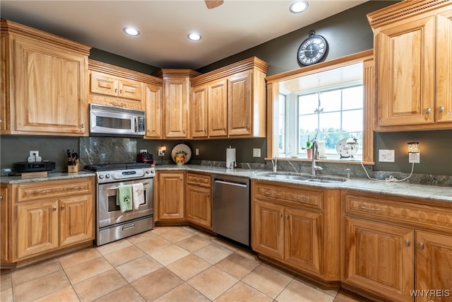 kitchen featuring sink, stainless steel appliances, light tile patterned floors, and light stone countertops