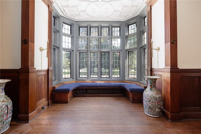 935 E Ave, Rochester, NY 14607 - living area featuring wainscoting, wood finished floors, decorative columns, a decorative wall, and a towering ceiling