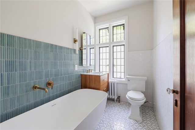 935 E Ave, Rochester, NY 14607 - bathroom with radiator heating unit, tile walls, toilet, plenty of natural light, and a freestanding bath