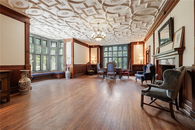 sitting room with a notable chandelier, wood-type flooring, a wealth of natural light, and a premium fireplace