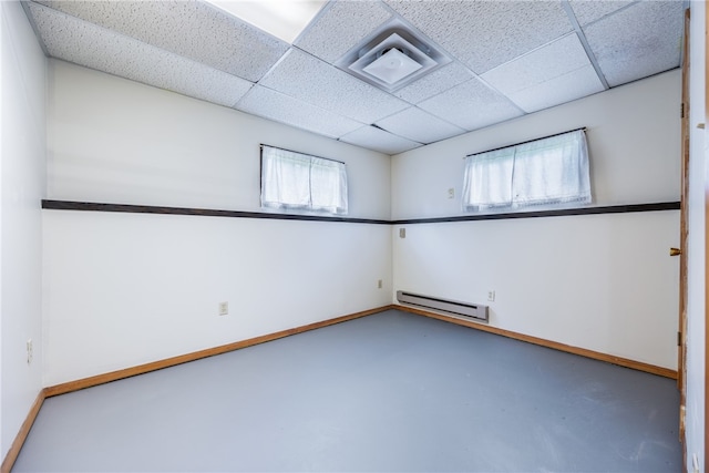 unfurnished room with a baseboard heating unit, concrete flooring, and a drop ceiling