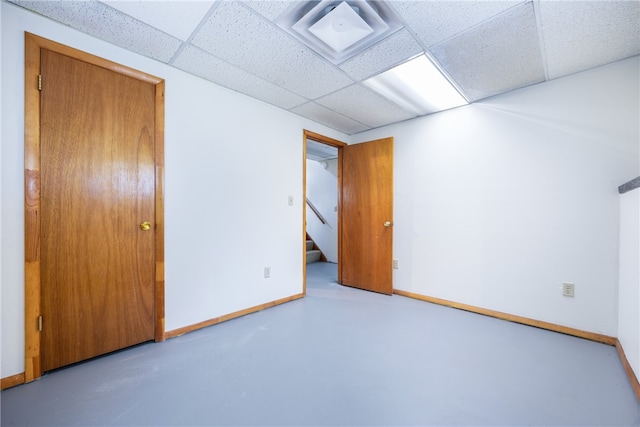 spare room with concrete flooring and a paneled ceiling