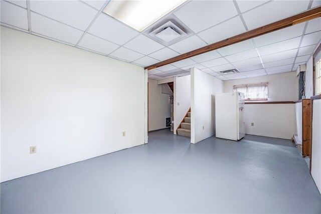 basement featuring white refrigerator and a paneled ceiling