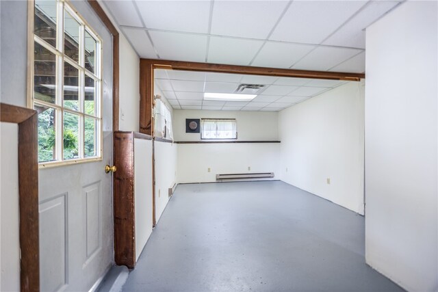 unfurnished room with a baseboard radiator, concrete floors, and a drop ceiling