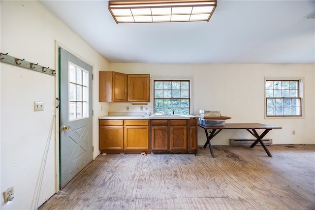 kitchen with sink, a baseboard heating unit, and light hardwood / wood-style floors