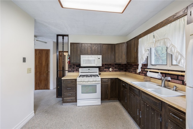 kitchen featuring ceiling fan, light carpet, sink, white appliances, and dark brown cabinets