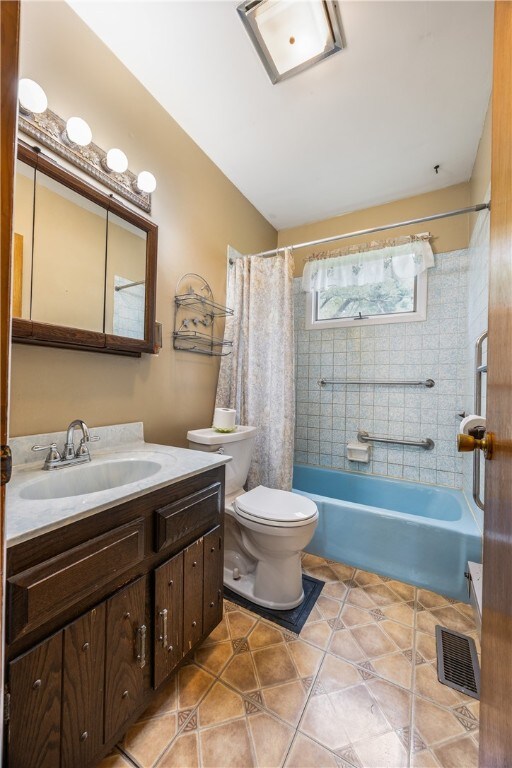 full bathroom featuring tile patterned floors, toilet, shower / bathtub combination with curtain, and vanity