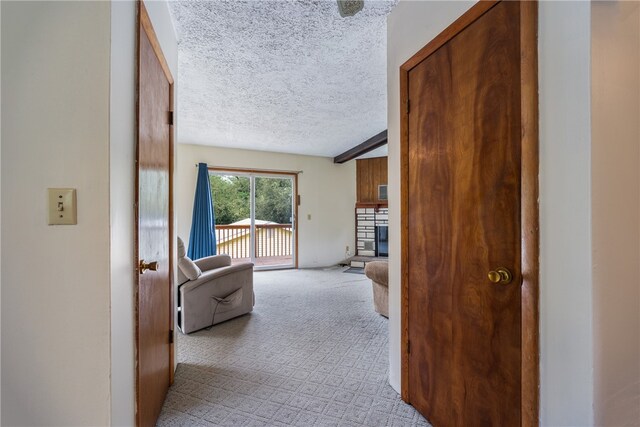 corridor featuring a textured ceiling and light carpet