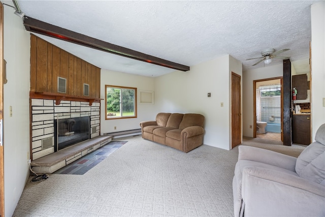 living room featuring a fireplace, beam ceiling, baseboard heating, ceiling fan, and light colored carpet