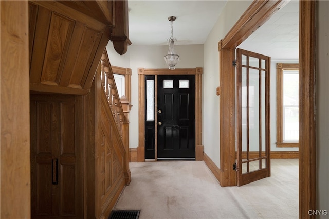 entryway with light carpet, stairs, visible vents, and baseboards