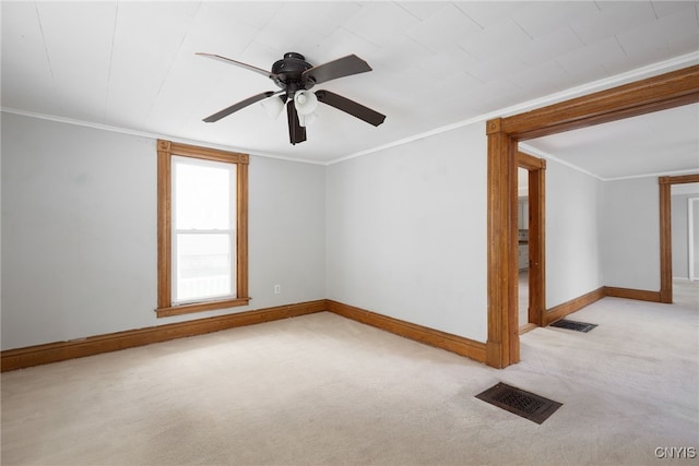 carpeted empty room featuring baseboards, visible vents, ceiling fan, and crown molding