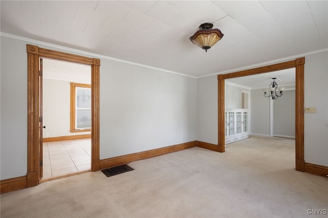 spare room featuring a notable chandelier, visible vents, ornamental molding, carpet flooring, and baseboards