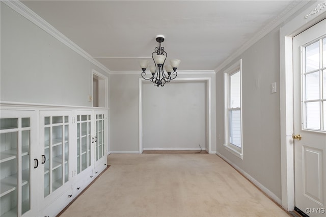 unfurnished dining area with ornamental molding, a chandelier, carpet floors, and baseboards