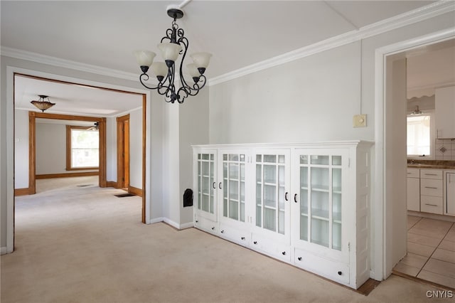 hallway with light carpet, crown molding, baseboards, and an inviting chandelier