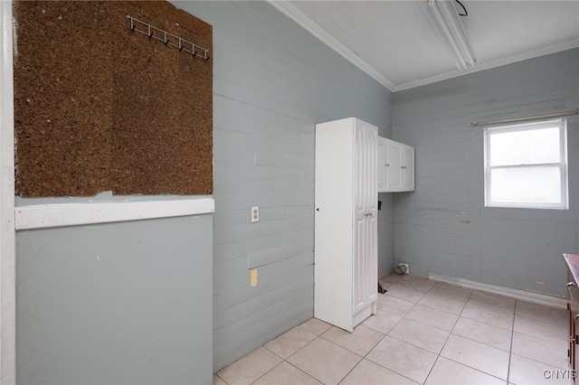 laundry area with light tile patterned floors and crown molding