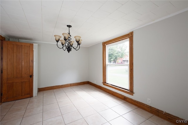 empty room with a notable chandelier, crown molding, baseboards, and light tile patterned floors