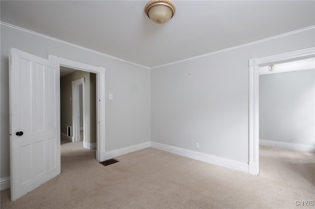 carpeted spare room featuring visible vents, crown molding, and baseboards