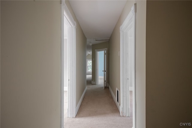 corridor with light carpet, baseboards, and visible vents