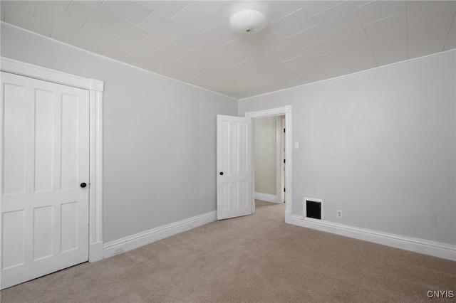 carpeted empty room featuring baseboards and visible vents