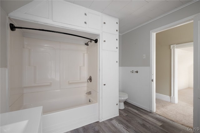 bathroom featuring toilet, ornamental molding, tub / shower combination, wood finished floors, and baseboards