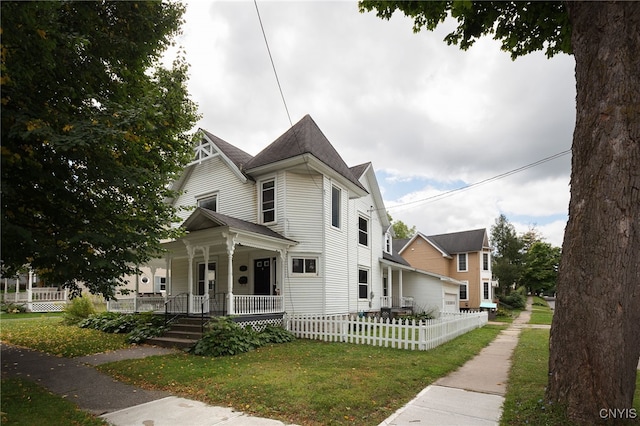 victorian house featuring a front yard, covered porch, and fence