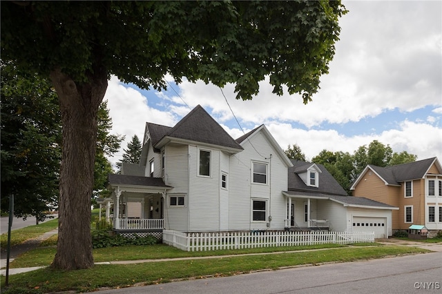 victorian-style house with a porch, a fenced front yard, an attached garage, concrete driveway, and a front yard