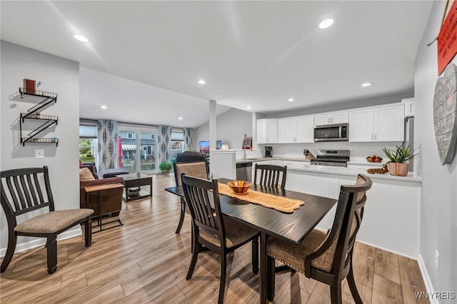 dining room featuring light wood-type flooring and lofted ceiling