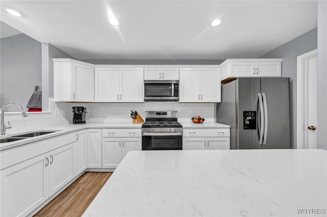 kitchen with light hardwood / wood-style flooring, white cabinets, appliances with stainless steel finishes, and sink