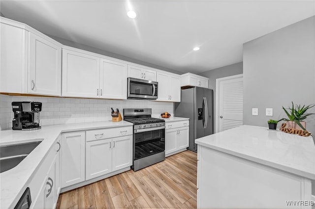 kitchen featuring decorative backsplash, white cabinets, appliances with stainless steel finishes, and light wood-type flooring