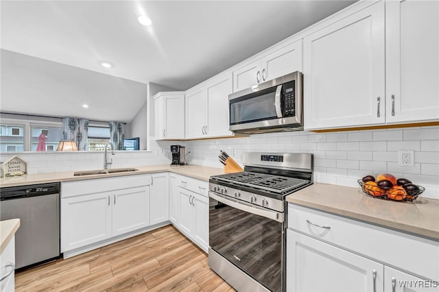 kitchen with light hardwood / wood-style floors, sink, white cabinetry, stainless steel appliances, and backsplash