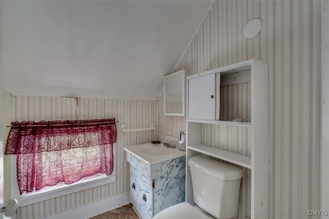 bathroom featuring toilet, vanity, and lofted ceiling