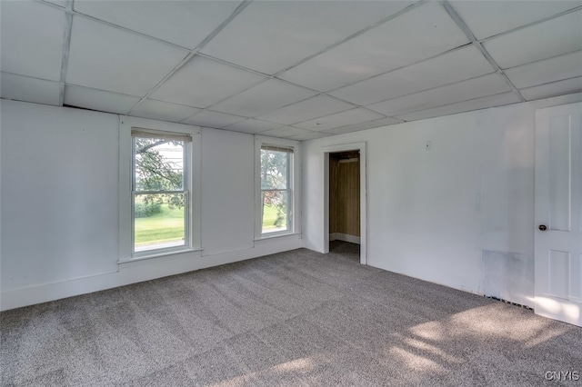 carpeted spare room featuring a drop ceiling and a healthy amount of sunlight