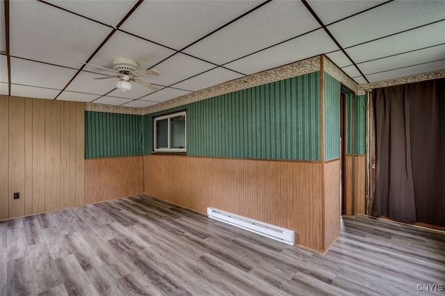 spare room featuring a drop ceiling, ceiling fan, a baseboard radiator, and hardwood / wood-style floors