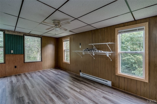 spare room with ceiling fan, light wood-type flooring, a baseboard heating unit, and a drop ceiling