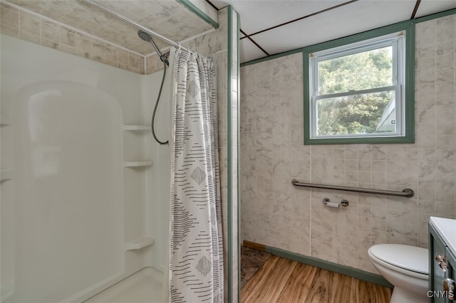 bathroom featuring curtained shower, hardwood / wood-style flooring, vanity, and tile walls